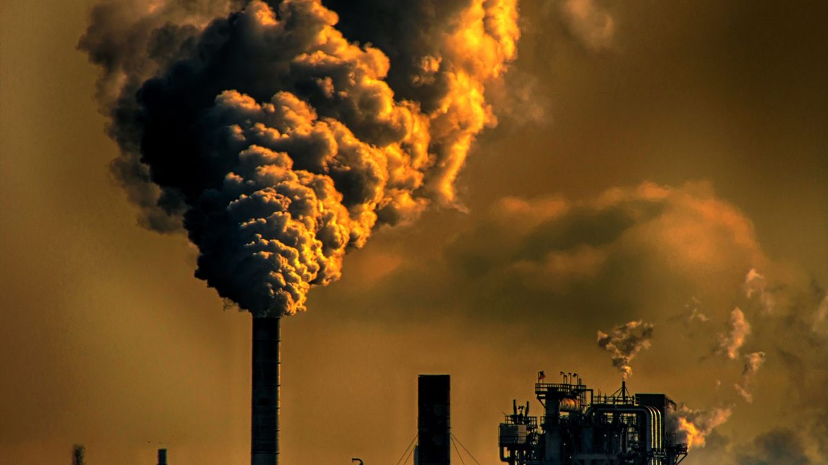 Chimeneas industriales liberan emisiones frente al cielo del atardecer.