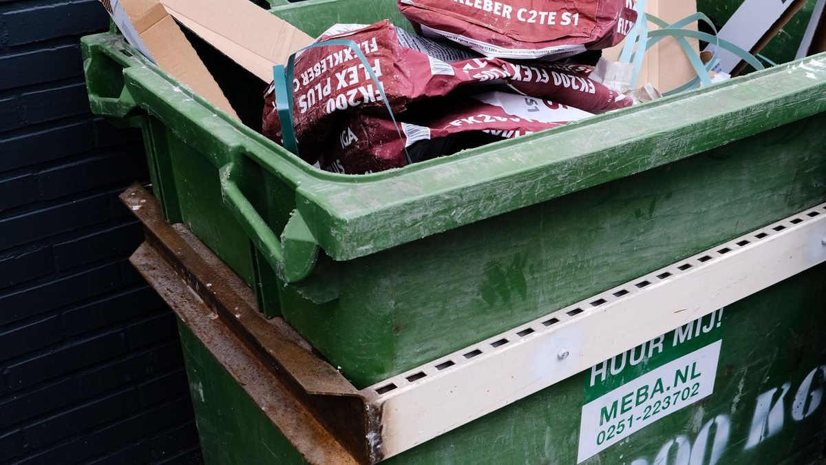 Cartón de embalaje depositado en un contenedor verde.