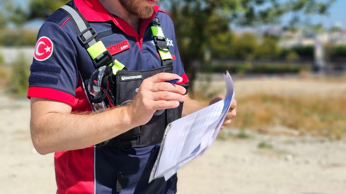 Trabajador con casco y chaleco revisa documentos en una obra.